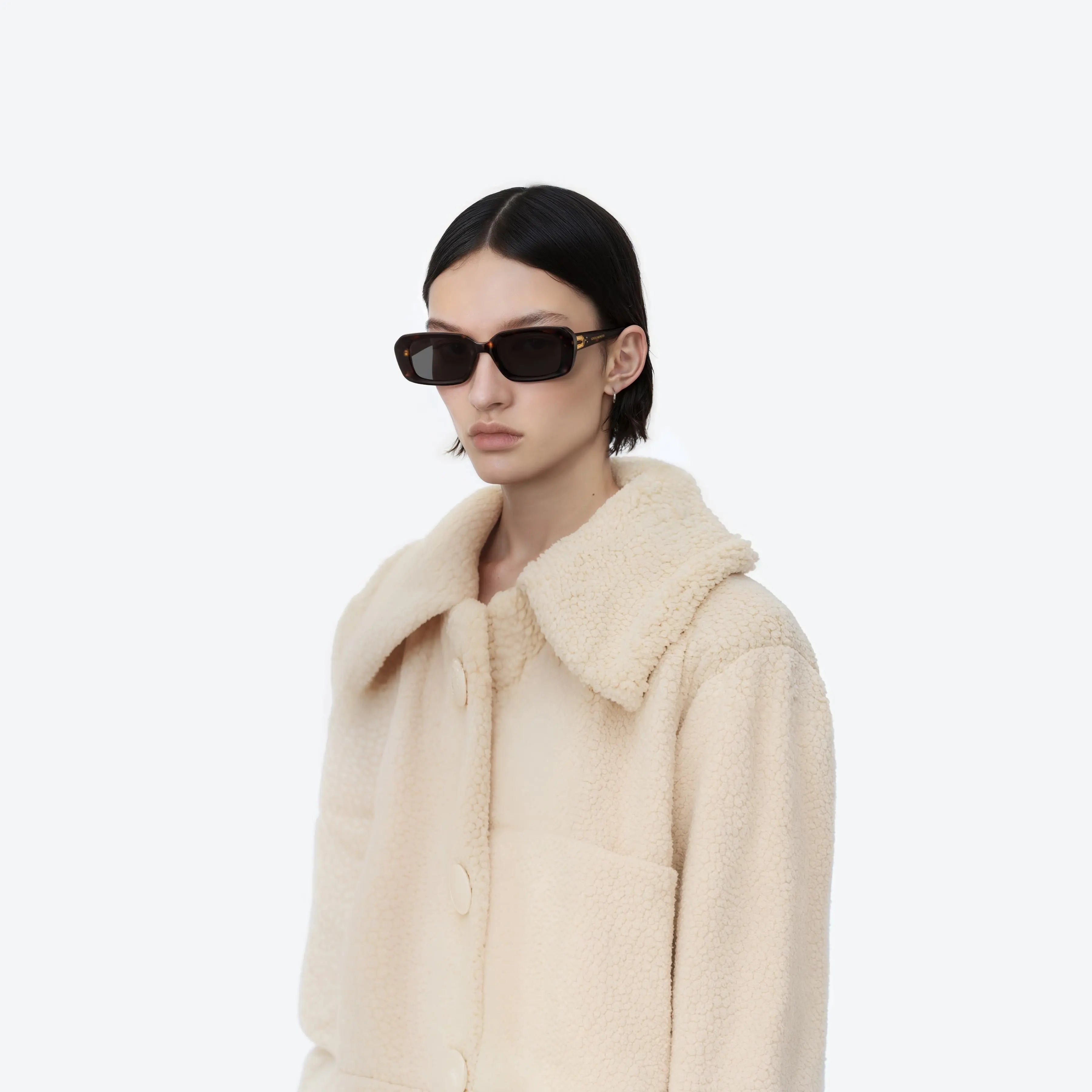 Lunettes de Soleil Femme Gentle Monster Melrose T1 à monture sombre portées par mannequin en manteau beige